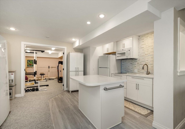 kitchen with a center island, sink, white appliances, white cabinets, and decorative backsplash