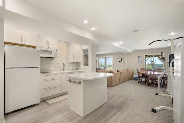 kitchen with white appliances, backsplash, white cabinetry, a kitchen island, and french doors