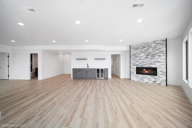 5022 S Lincoln Way, Spokane, WA 99224 - unfurnished living room with beverage cooler, light wood-style floors, bar, a tile fireplace, and recessed lighting