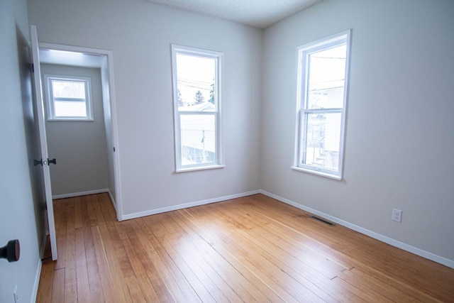 spare room with light hardwood / wood-style floors and a textured ceiling