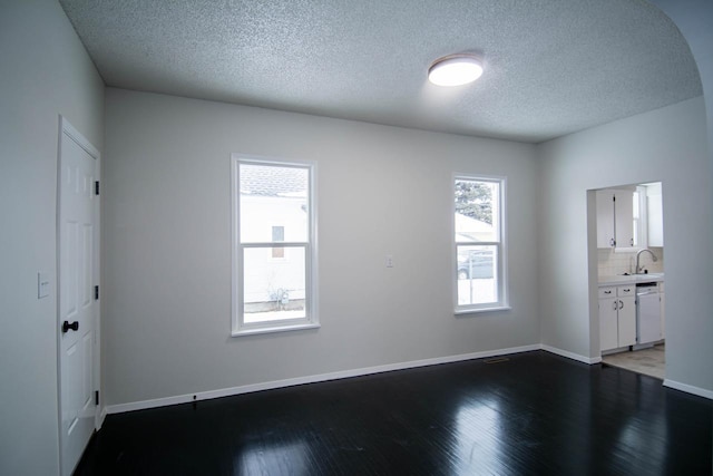 spare room with sink, a textured ceiling, and hardwood / wood-style floors