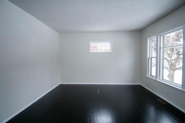 unfurnished room with dark wood-type flooring and a textured ceiling