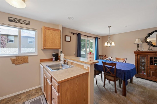 kitchen with decorative light fixtures, sink, light brown cabinetry, and kitchen peninsula