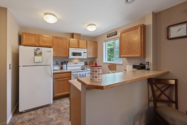 kitchen with white appliances, a breakfast bar area, and kitchen peninsula