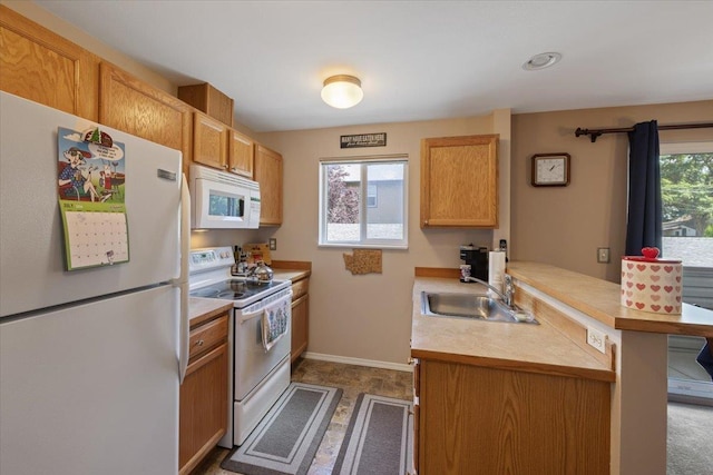 kitchen featuring a wealth of natural light, sink, white appliances, and kitchen peninsula