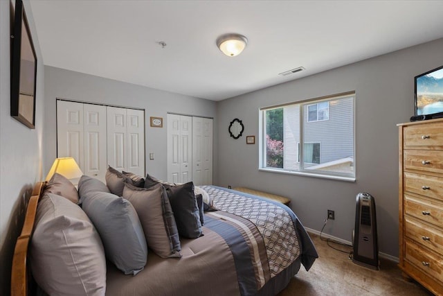 bedroom featuring carpet and two closets