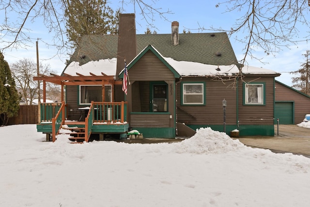 snow covered rear of property featuring a pergola and a garage