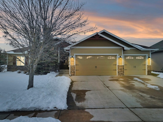 craftsman inspired home with a garage, concrete driveway, and stone siding