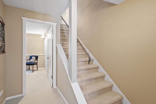 staircase featuring carpet and a textured ceiling