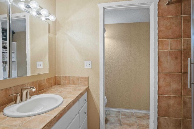 5107N Argonne Ln # 4, Spokane, WA 99212 - bathroom featuring vanity, toilet, a textured wall, baseboards, and tile patterned floors