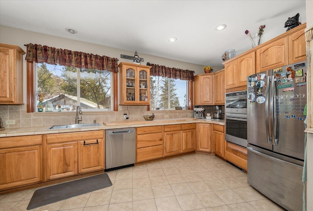 kitchen with appliances with stainless steel finishes, light tile patterned floors, sink, and backsplash