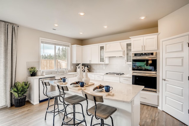 kitchen featuring stainless steel appliances, sink, backsplash, custom exhaust hood, and white cabinets