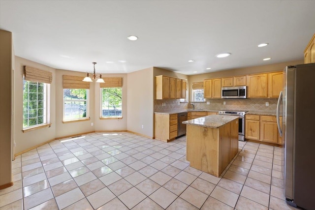 kitchen featuring light tile patterned floors, sink, a center island, decorative light fixtures, and stainless steel appliances