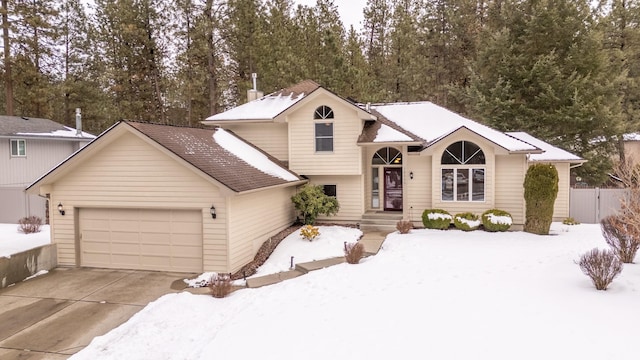 split level home featuring an attached garage, fence, and concrete driveway