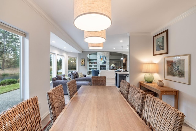 dining area featuring ornamental molding, a stone fireplace, and a healthy amount of sunlight