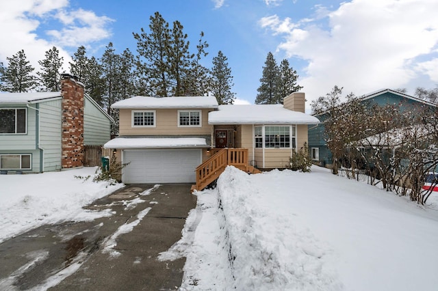 tri-level home featuring a garage, driveway, and a chimney