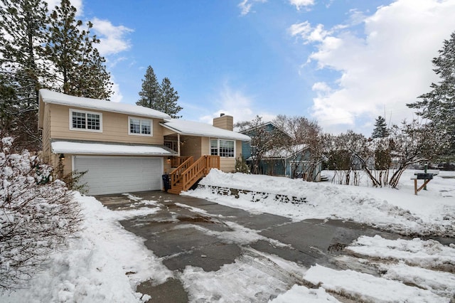 view of front of home with driveway, a chimney, and an attached garage