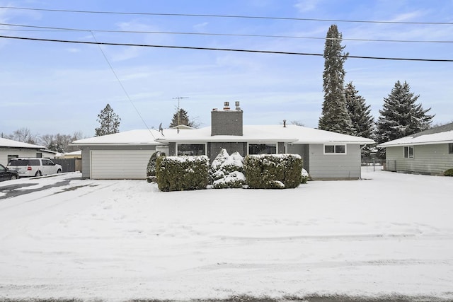 ranch-style home with a chimney and an attached garage