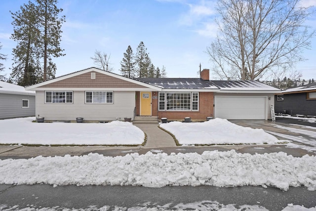 view of front of home with a garage, driveway, entry steps, a chimney, and brick siding