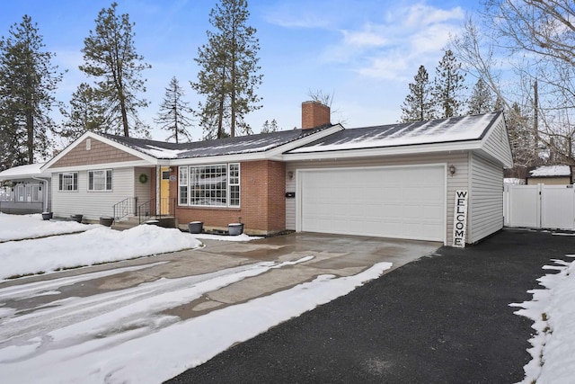 ranch-style house featuring a garage, brick siding, fence, driveway, and a chimney