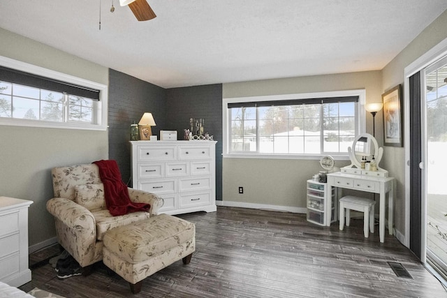 sitting room with a ceiling fan, visible vents, baseboards, and dark wood-type flooring