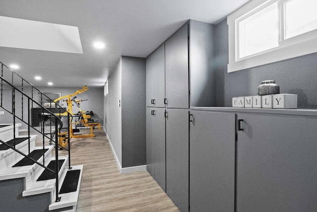 hall featuring light wood-style floors, recessed lighting, baseboards, and stairs