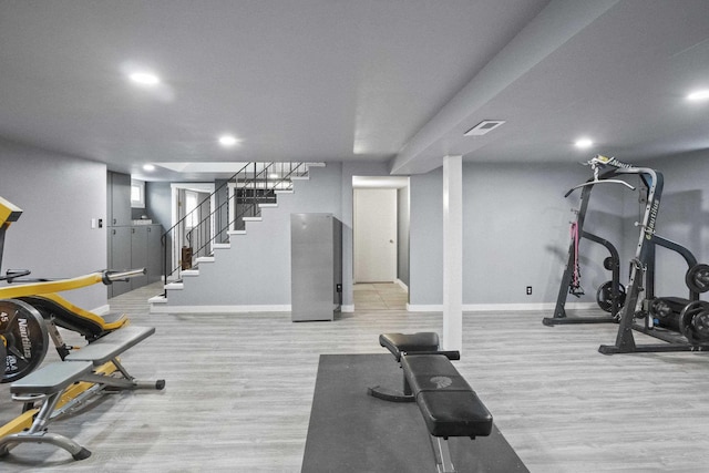 workout area featuring visible vents, light wood finished floors, and baseboards