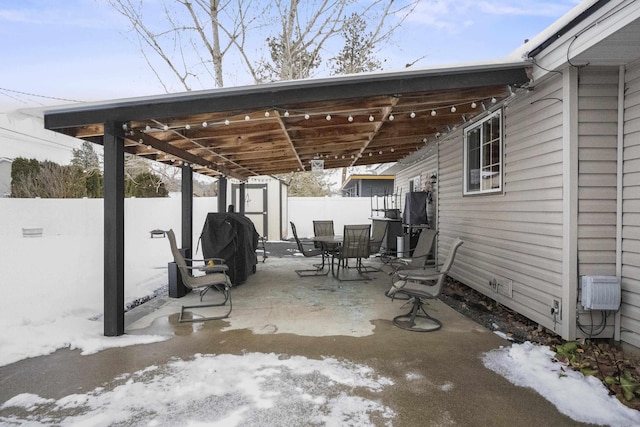 snow covered patio featuring a fenced backyard and outdoor dining space