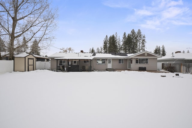 snow covered property featuring a shed, fence, and an outbuilding