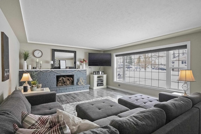 living area with light wood-type flooring, a brick fireplace, baseboards, and a textured ceiling