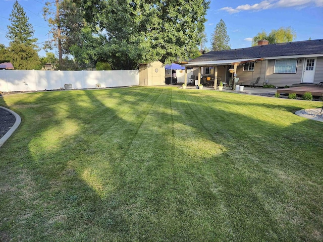 view of yard featuring a patio area, a fenced backyard, an outdoor structure, and a storage unit