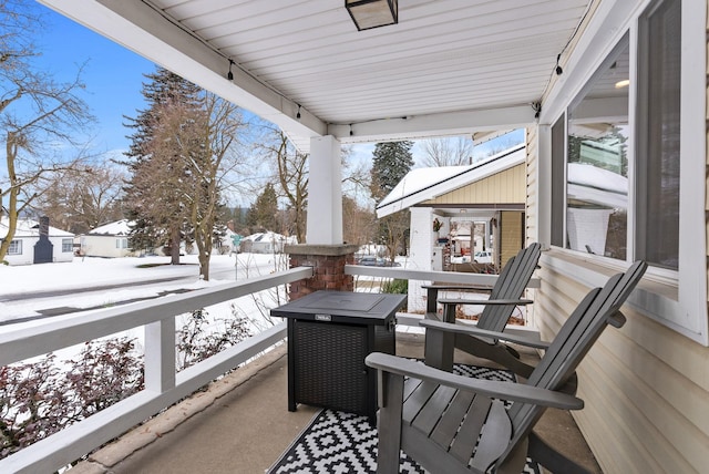 snow covered back of property with a porch