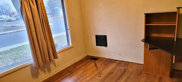 empty room with visible vents, dark wood finished floors, and baseboards