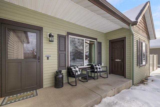 snow covered property entrance with covered porch