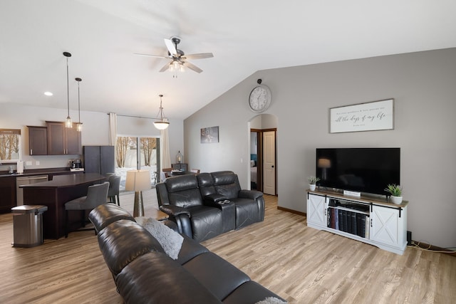 living area with light wood finished floors, arched walkways, vaulted ceiling, and a ceiling fan