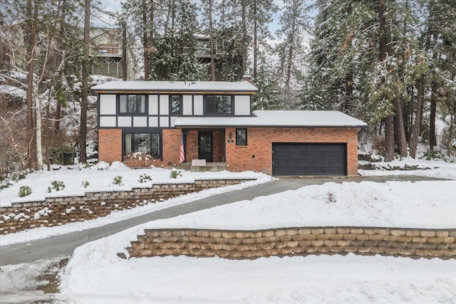 english style home with a garage, driveway, and brick siding