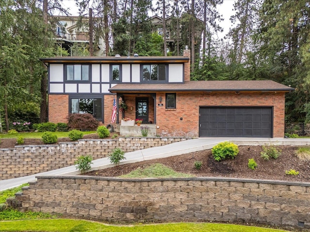 tudor house with an attached garage, a chimney, concrete driveway, and brick siding