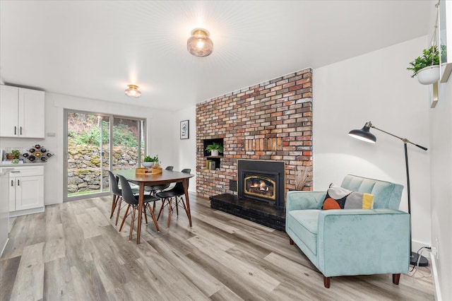 dining space with a brick fireplace and light wood-style flooring