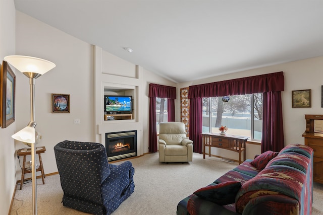 living room with lofted ceiling, baseboards, a glass covered fireplace, and light colored carpet