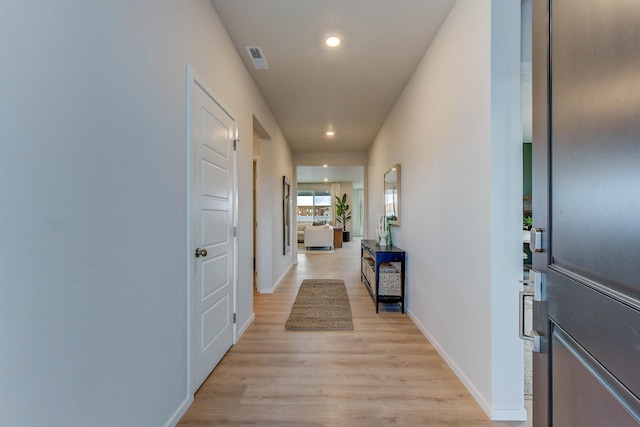 hall featuring light wood finished floors, baseboards, visible vents, and recessed lighting