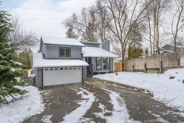 view of front of home featuring a garage, driveway, a chimney, and fence