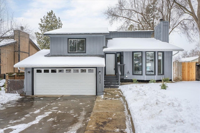 view of front of home with a garage, fence, and a chimney