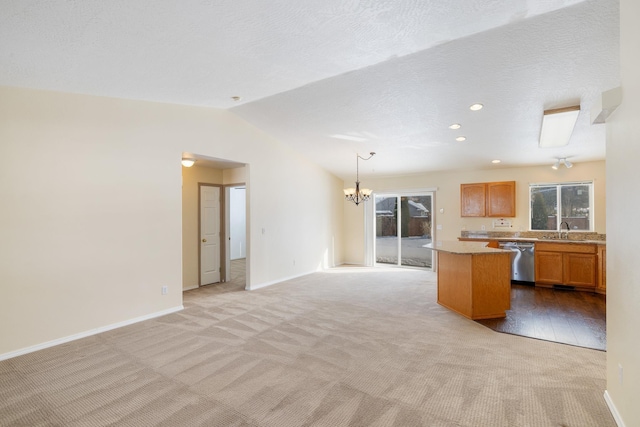 kitchen featuring a sink, open floor plan, light countertops, dishwasher, and decorative light fixtures