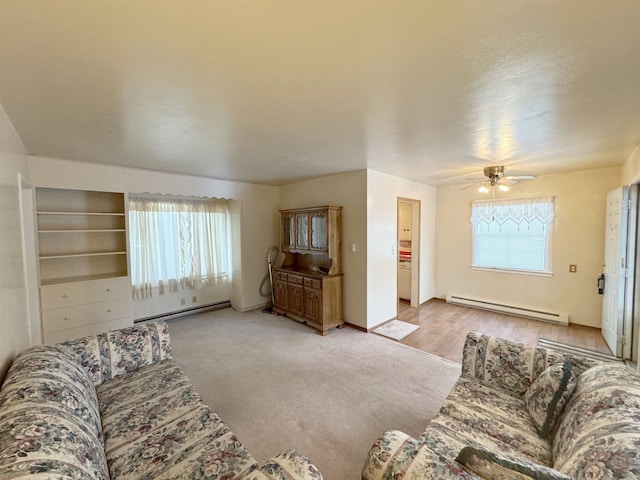 living area featuring a wealth of natural light, a baseboard radiator, baseboard heating, and a ceiling fan