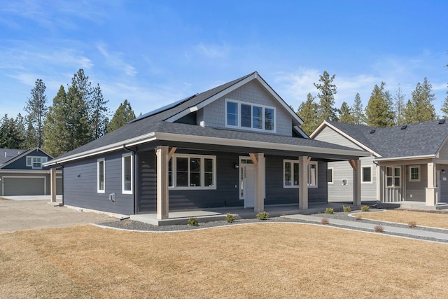 view of front of house with covered porch, a shingled roof, and a front lawn