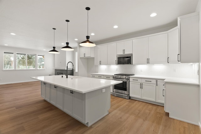 kitchen with high end stainless steel range oven, light countertops, light wood-style floors, and decorative backsplash