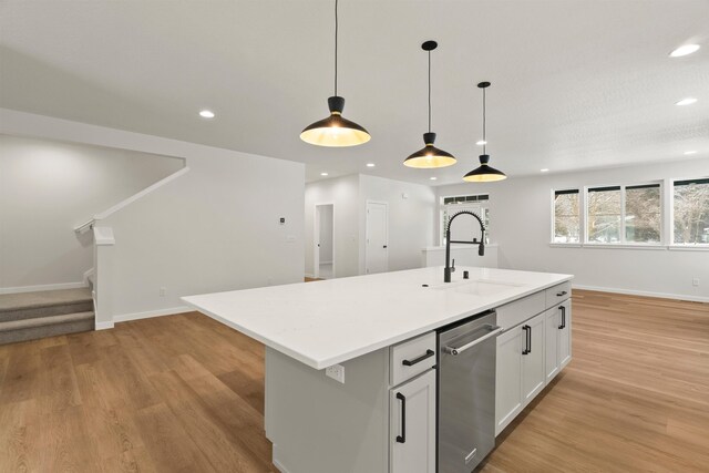 kitchen featuring stainless steel dishwasher, light wood-style flooring, open floor plan, and a sink