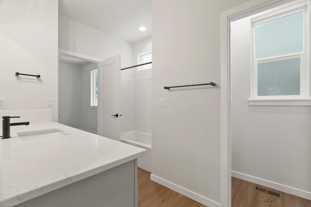 bathroom with visible vents, tub / shower combination, baseboards, and wood finished floors