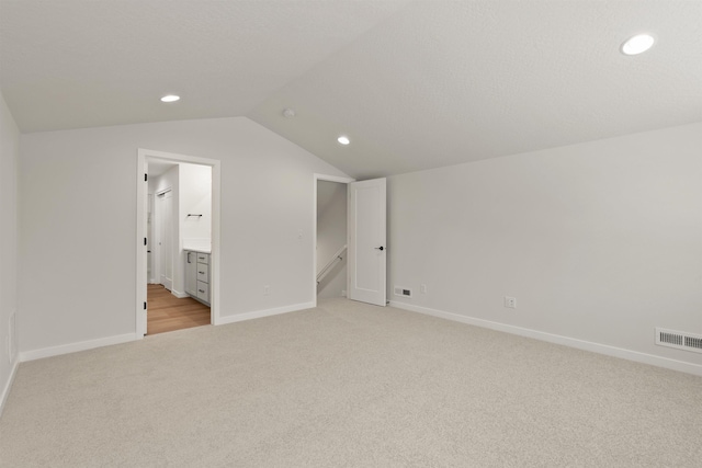 interior space featuring visible vents, recessed lighting, baseboards, lofted ceiling, and light colored carpet