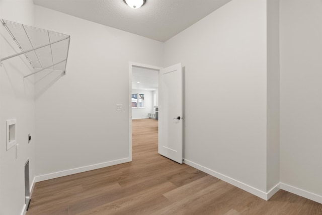 clothes washing area featuring laundry area, baseboards, and light wood finished floors